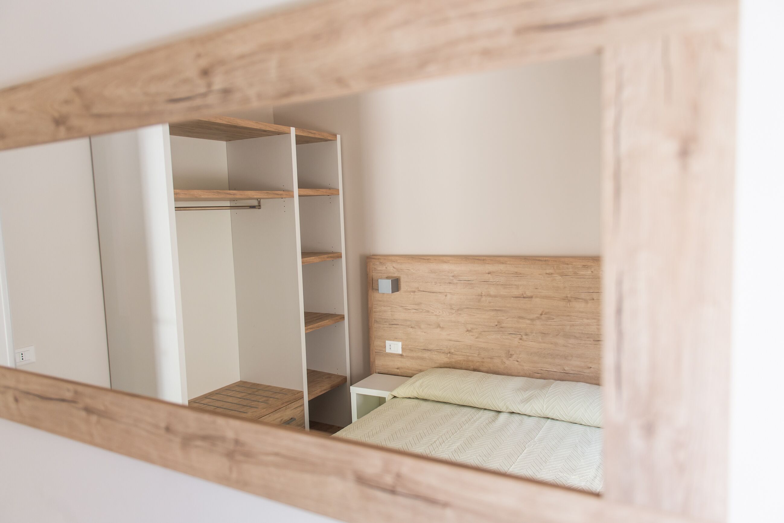 A bedroom with a wooden headboard, a bed with a patterned bedspread, and a white nightstand.