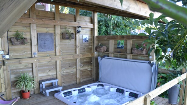 A wooden deck with a hot tub, a small table, and potted plants. - La Caz Océane (Saint-Leu)