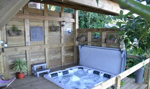 A wooden deck with a hot tub, a small table, and potted plants. - La Caz Océane (Saint-Leu)