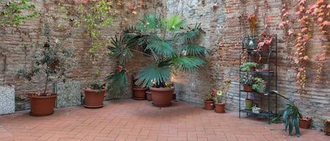 A courtyard with potted plants and a brick wall.