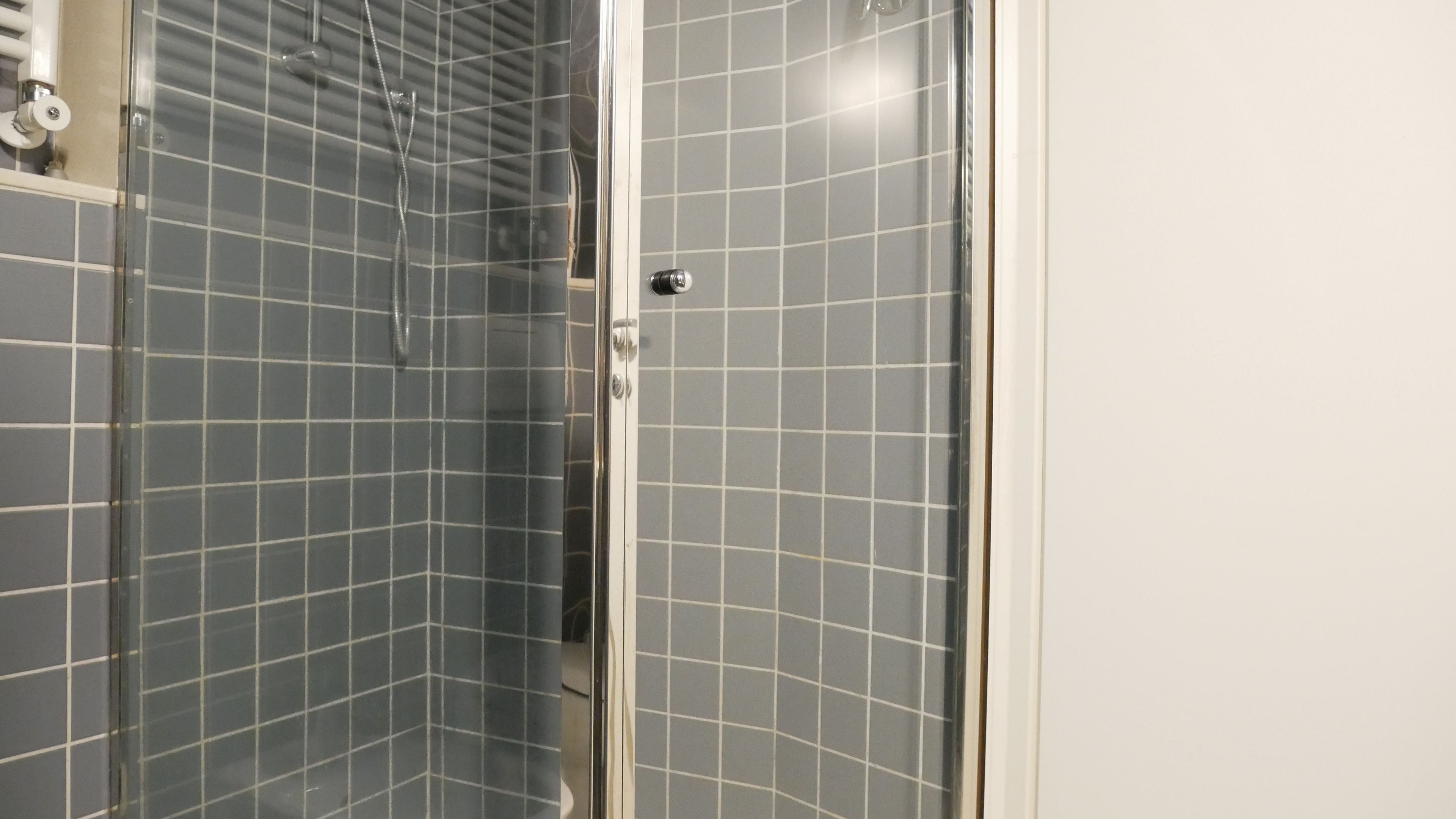 Eine Dusche mit Glastür und gefliesten Wänden.