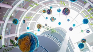 A multi-level atrium with a central spiral staircase, hanging spherical decorations, and potted plants. - Sirius Beach Hotel & SPA (Varna)