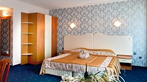 A bedroom with a bed, a wardrobe, and a nightstand. - Sirius Beach Hotel & SPA (Varna)