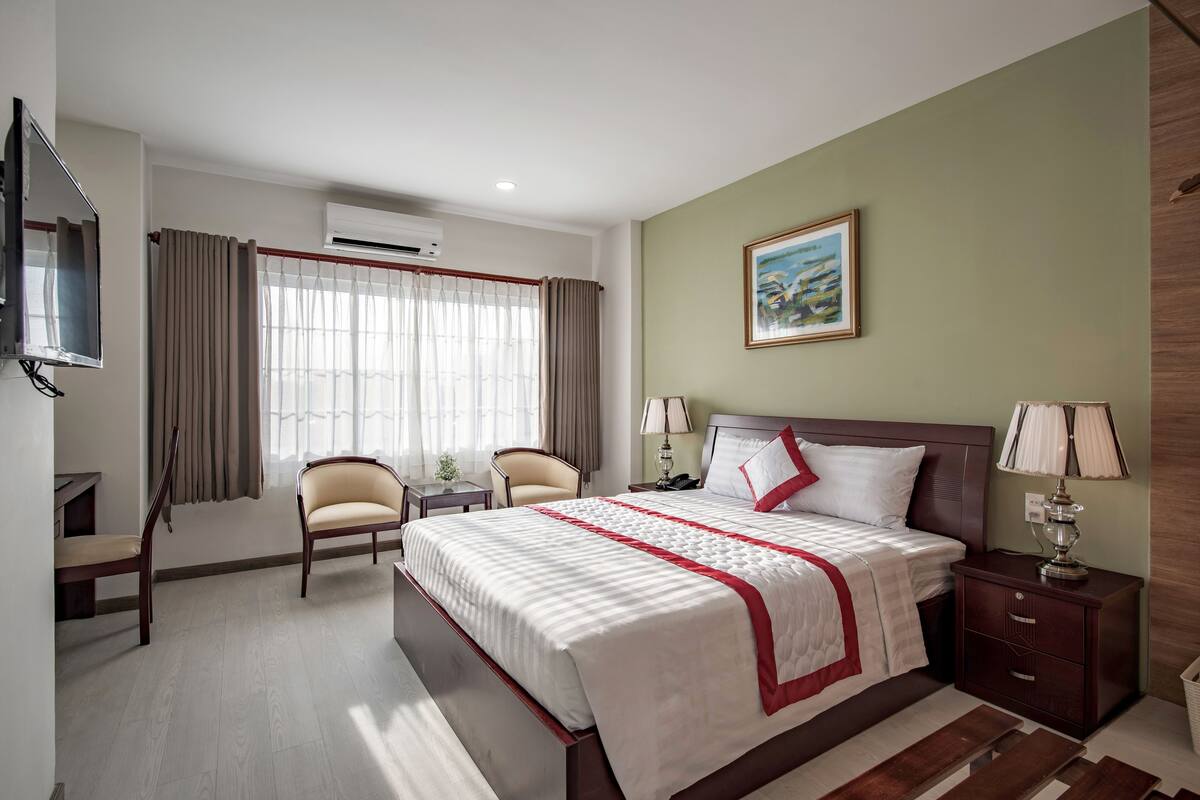 Een hotelkamer met een bed, een bureau, een stoel, een televisie en een raam met gordijnen.