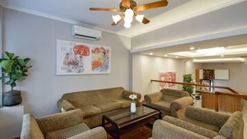 A spacious living area with patterned sofas, a coffee table, and a ceiling fan.