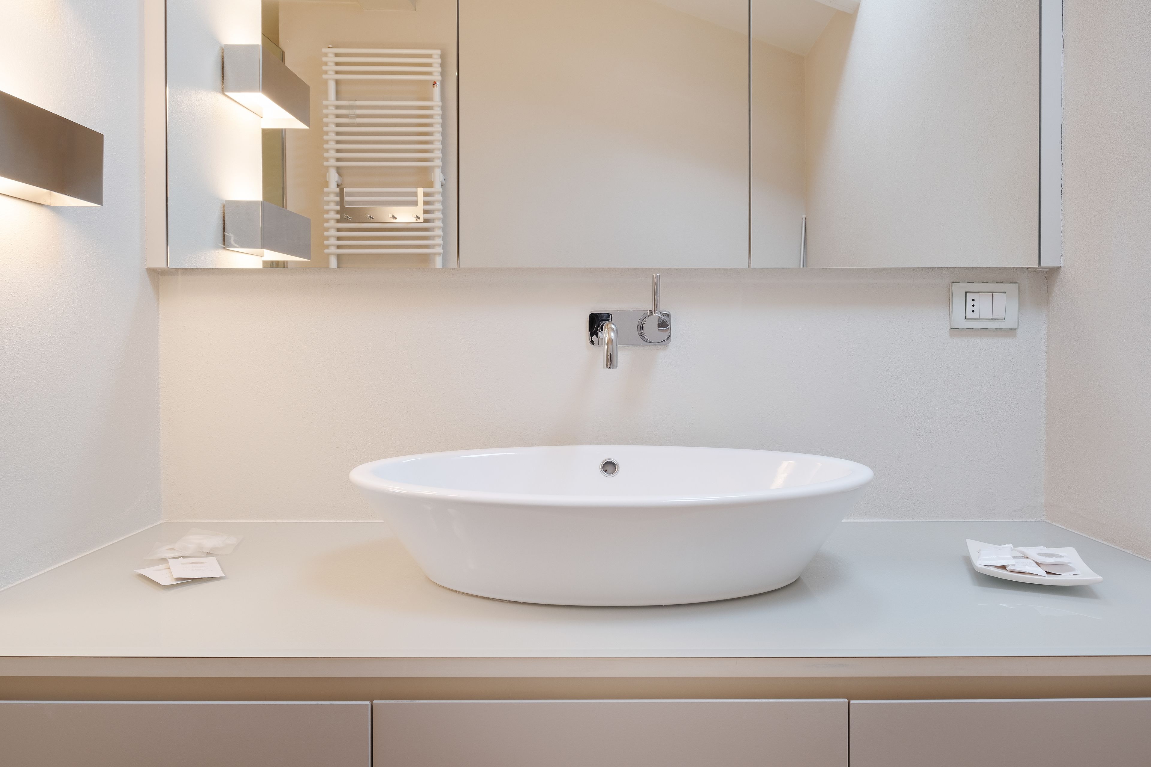 A modern bathroom with a white sink, a mirror, and a towel rack.