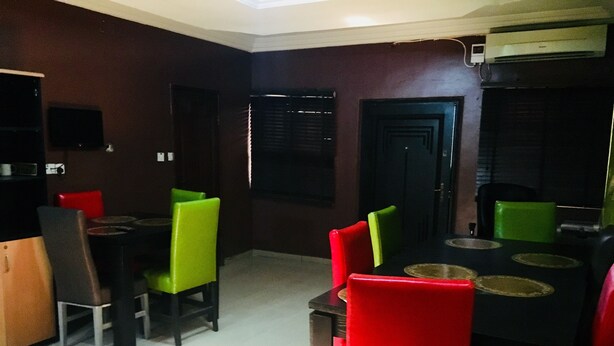 Un coin repas avec une table et des chaises, une porte sombre et un appareil de climatisation fixé au mur.