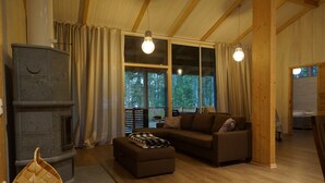Ein gemütliches Wohnzimmer mit Kamin, Holzböden, einer Couch und einem großen Fenster mit Vorhängen.
