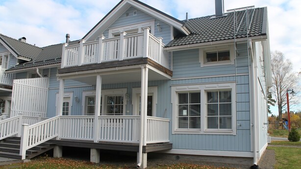 Ein zweistöckiges Haus mit Balkon, Veranda und Garage.