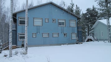 Ein zweistöckiges blaues Haus mit zahlreichen Fenstern und einer sichtbaren Treppe zum Eingang.