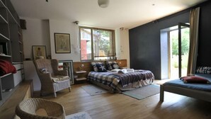 Un dormitorio con cama, una silla, un escritorio y una ventana.