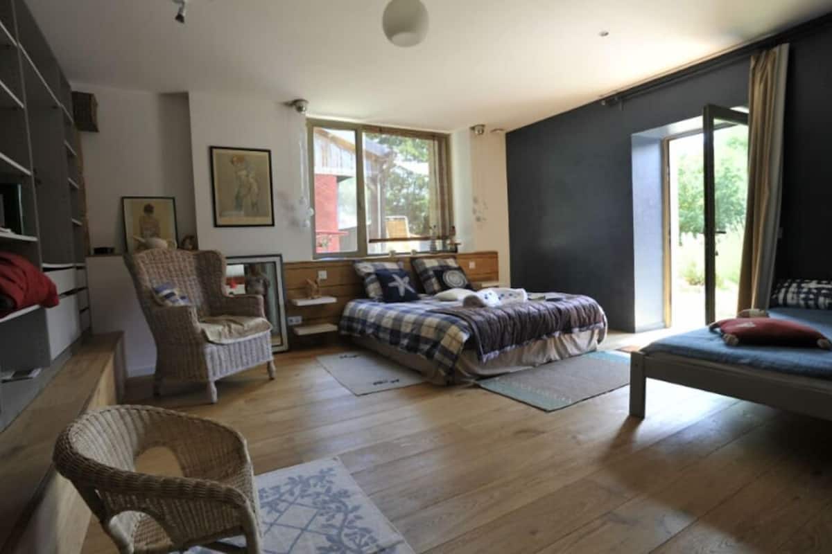 A bedroom with a bed, a chair, a desk, and a window.