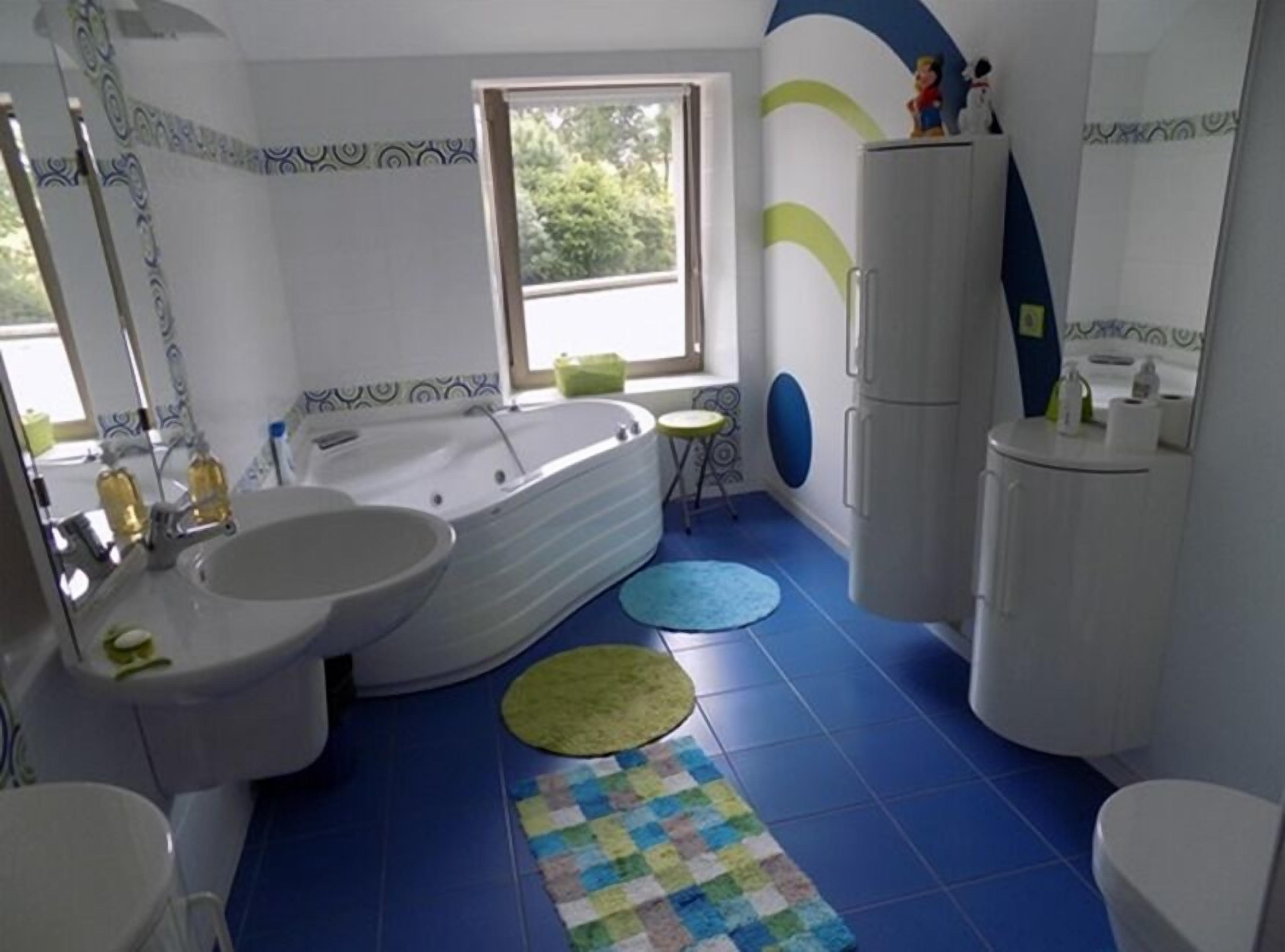 A bathroom with a bathtub, two sinks, a toilet, and a window.
