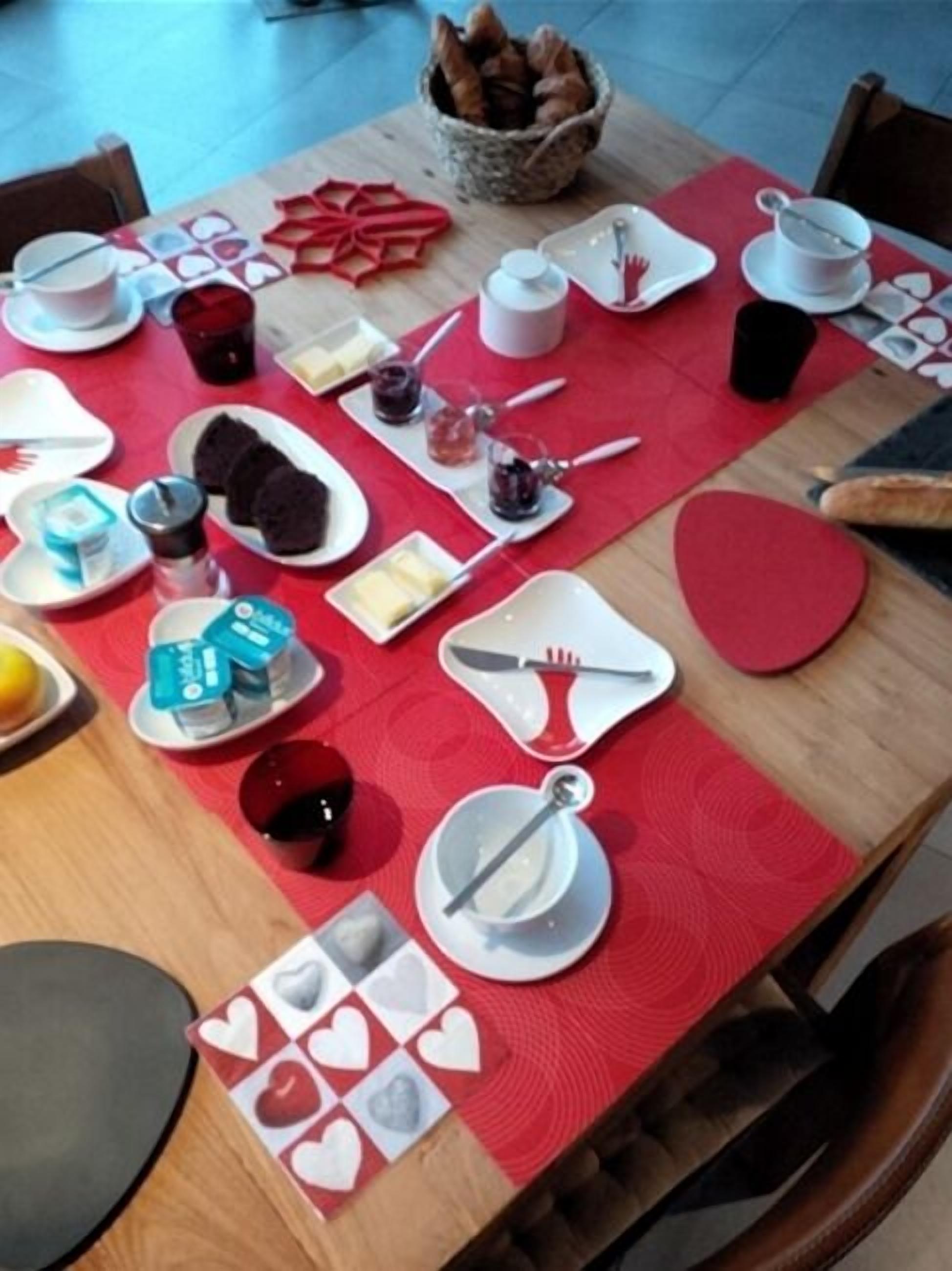 A dining table set with heart-shaped plates, cutlery, and various food items, suggesting a themed meal setup.