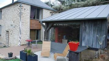 A stone house with a metal roof, a wooden deck, and outdoor seating.