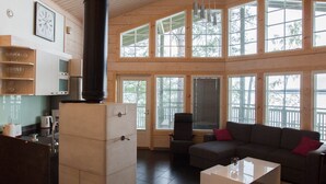 A modern interior with a kitchen, dining area, and a large windowed living space. - SResort Sauna Villas (Lappeenranta)
