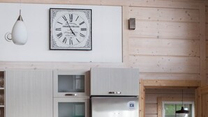 A modern kitchen with wooden cabinets, a stainless steel refrigerator, a Bosch oven, and a dining area with a table and chairs. - SResort Sauna Villas (Lappeenranta)
