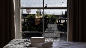 A hotel room with a large window overlooking the sea, a bed with neatly folded towels, and a view of a coastal promenade. - The Hope Hotel (Southend-on-Sea)