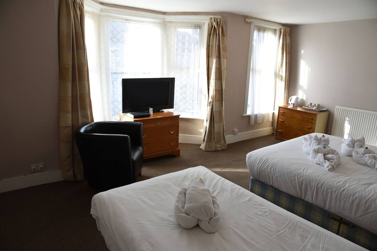 A hotel room with two beds, a TV, a dresser, and a chair.