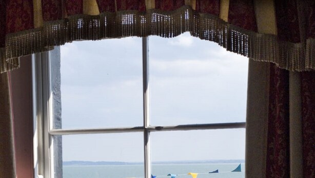 A window with a view of a beach, a blue sign, and a tree. - The Hope Hotel (Southend-on-Sea)
