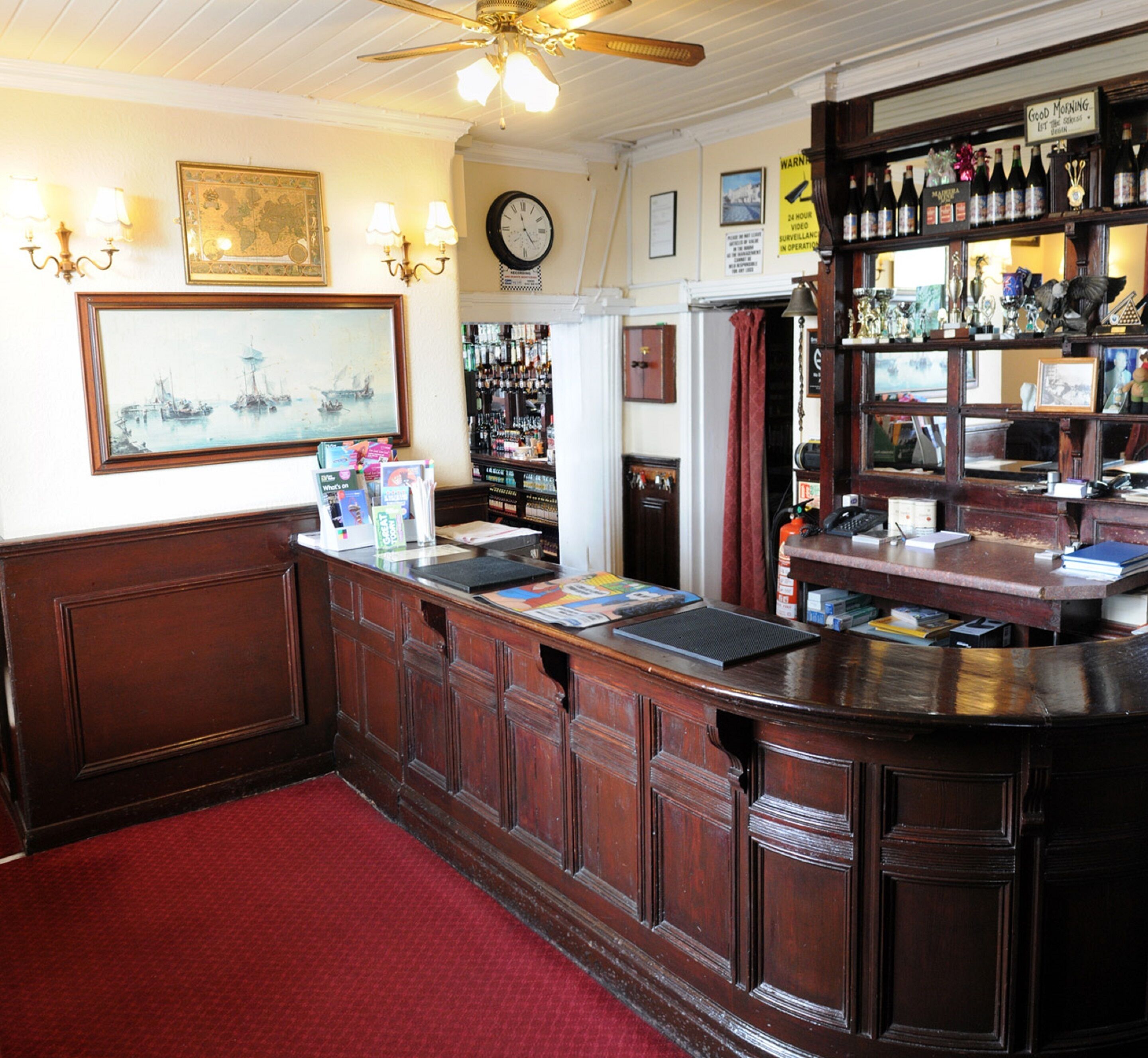 A bar area with wooden counters, a clock, and various bottles on shelves.