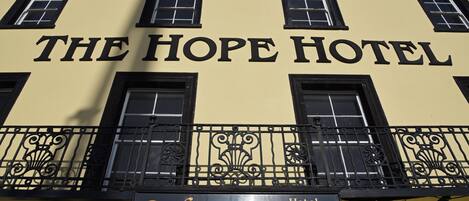 The exterior of The Hope Hotel with a 'Welcome' sign and a reception number.