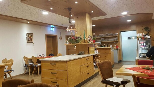 Un coin repas chaleureux avec des meubles en bois, un îlot central doté de tiroirs et, au fond, un espace cuisine.