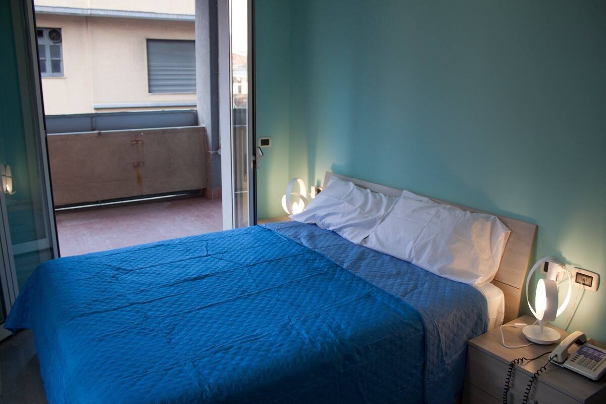 Quarto com cama, abajures e telefone na mesa de cabeceira.