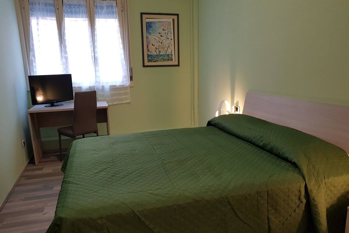Um quarto com uma cama, uma escrivaninha e uma cadeira.