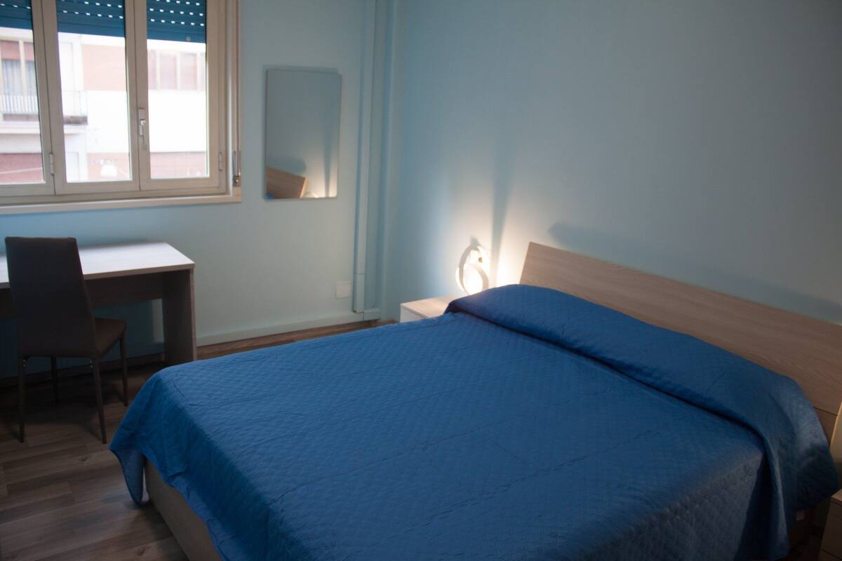 Quarto com uma cama, uma escrivaninha e uma cadeira.