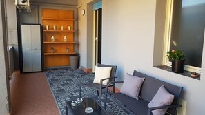 A balcony with a sofa, a small table, and a shelf with decorative items. - Seaside & City (Catania)