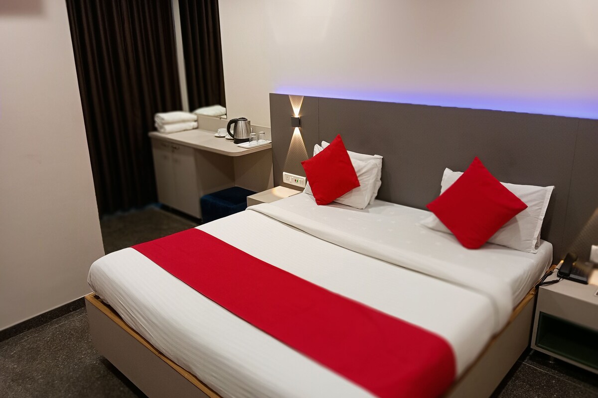 Una habitación de hotel con cama, mesita de noche, lámpara y vista del interior.