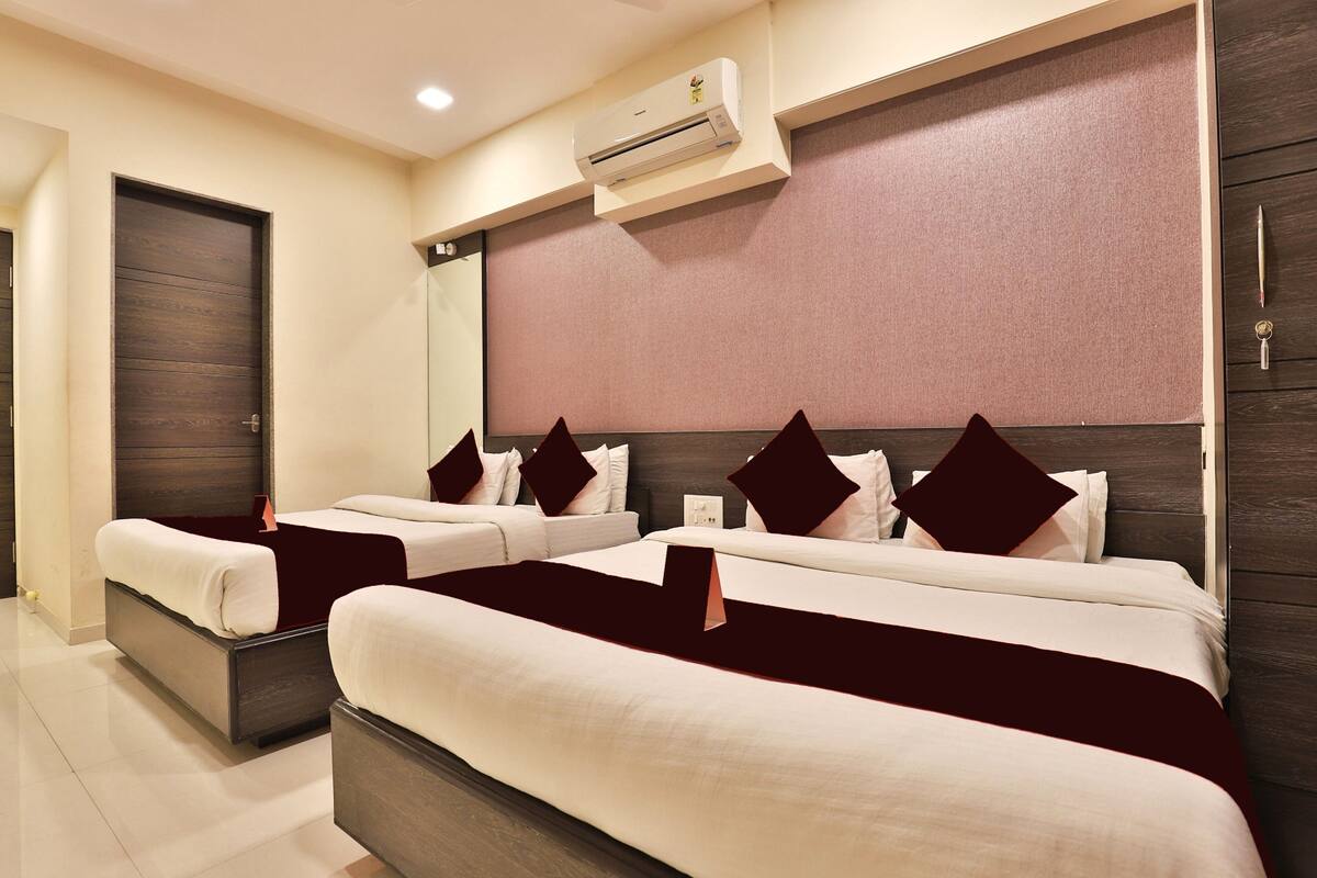 A hotel room with two beds, a large mirror, a wooden headboard, and an air conditioning unit.