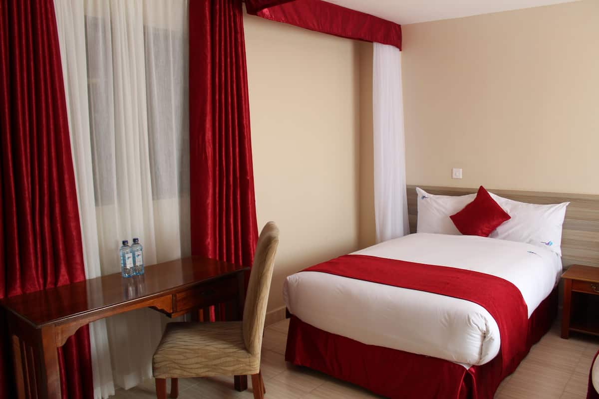 A hotel room with a bed, a desk, a chair, and a nightstand.