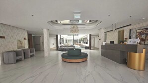 A spacious lobby with a central seating area, a reception desk, and a view into a dining area. - Snood Al Narjis Hotel (Riyadh)