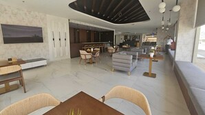 A modern hotel lobby with a dining area, seating arrangements, and a bar. - Snood Al Narjis Hotel (Riyadh)