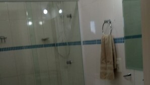 A bathroom with a glass-enclosed shower, a toilet, and a sink with a towel rack. - Apartamento Praia do Santinho (Florianópolis)
