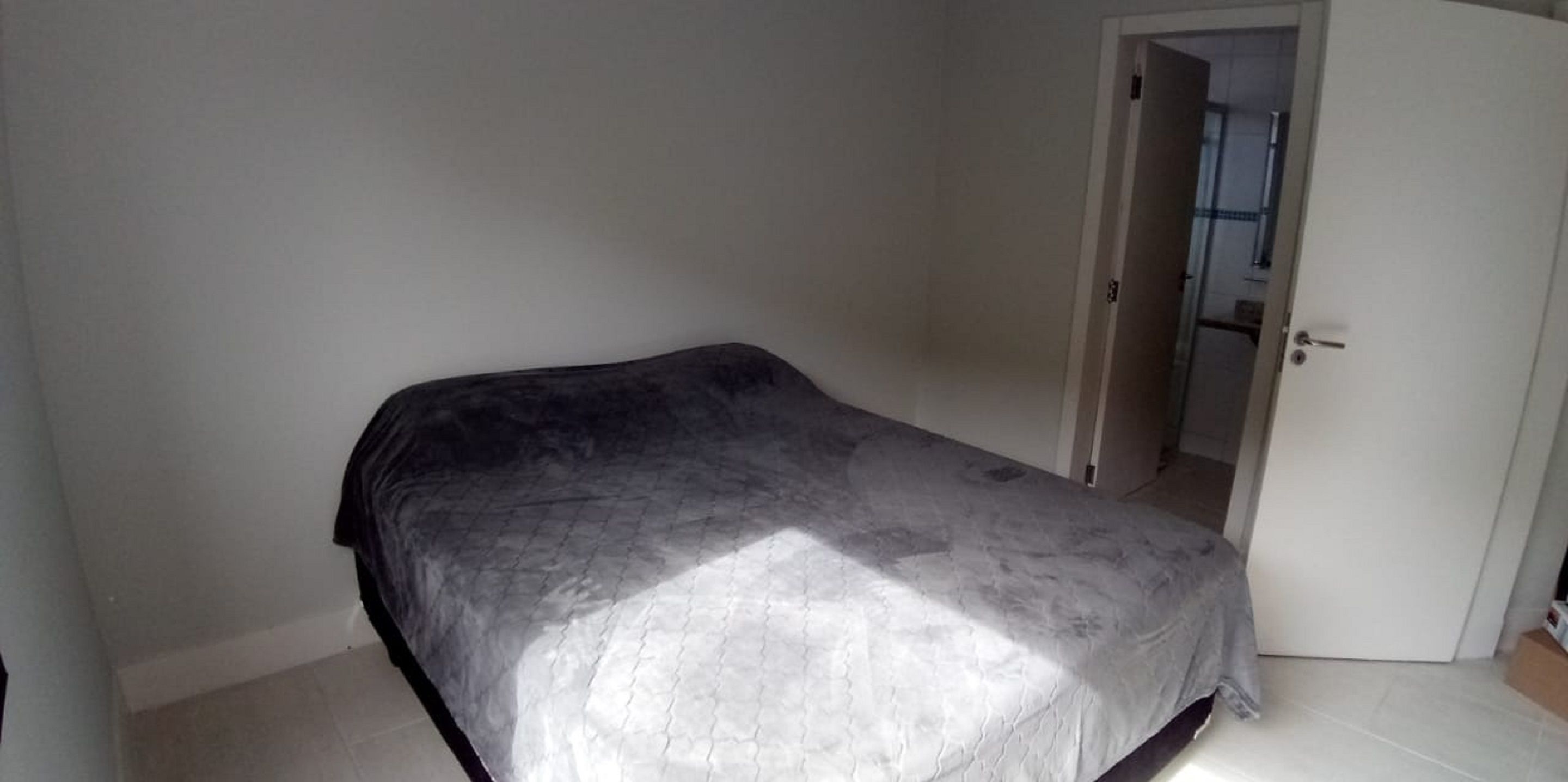 Een slaapkamer met een bed, een deur en uitzicht op een andere kamer.