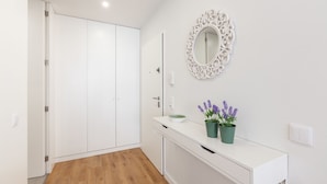 A modern bathroom with a white vanity, a mirror with an ornate frame, and a potted lavender plant.