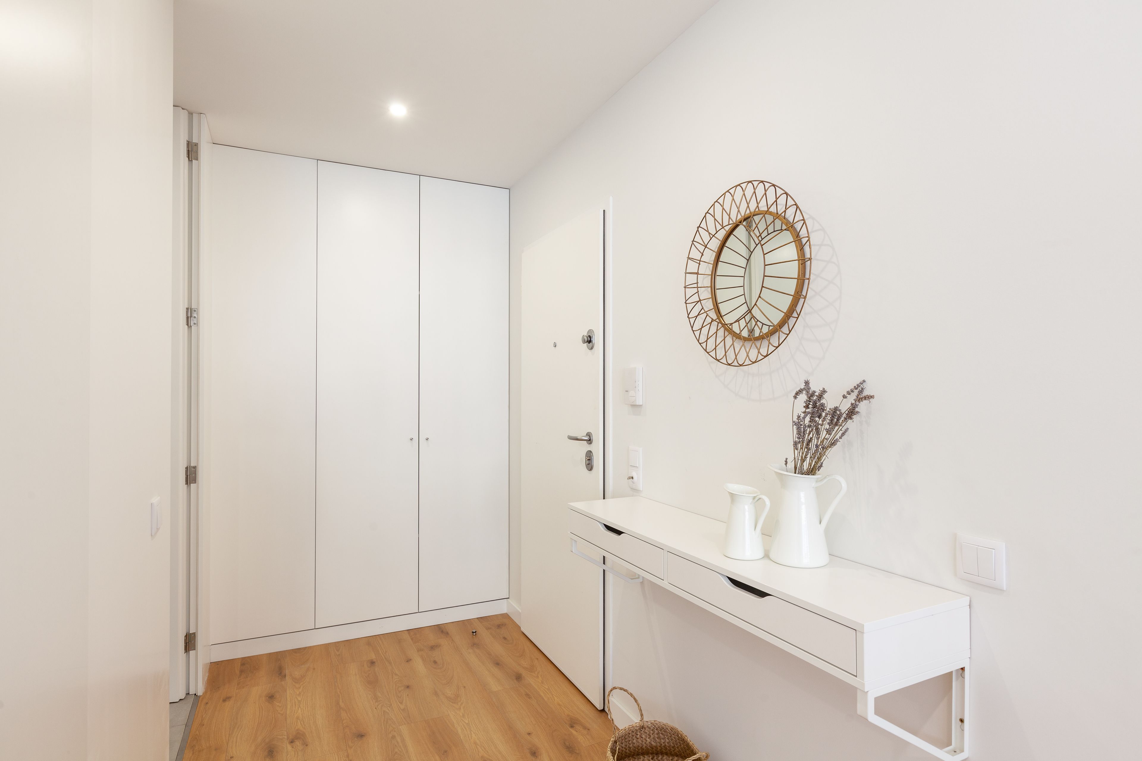 A modern bathroom with a white vanity, a mirror, and a decorative wall piece.