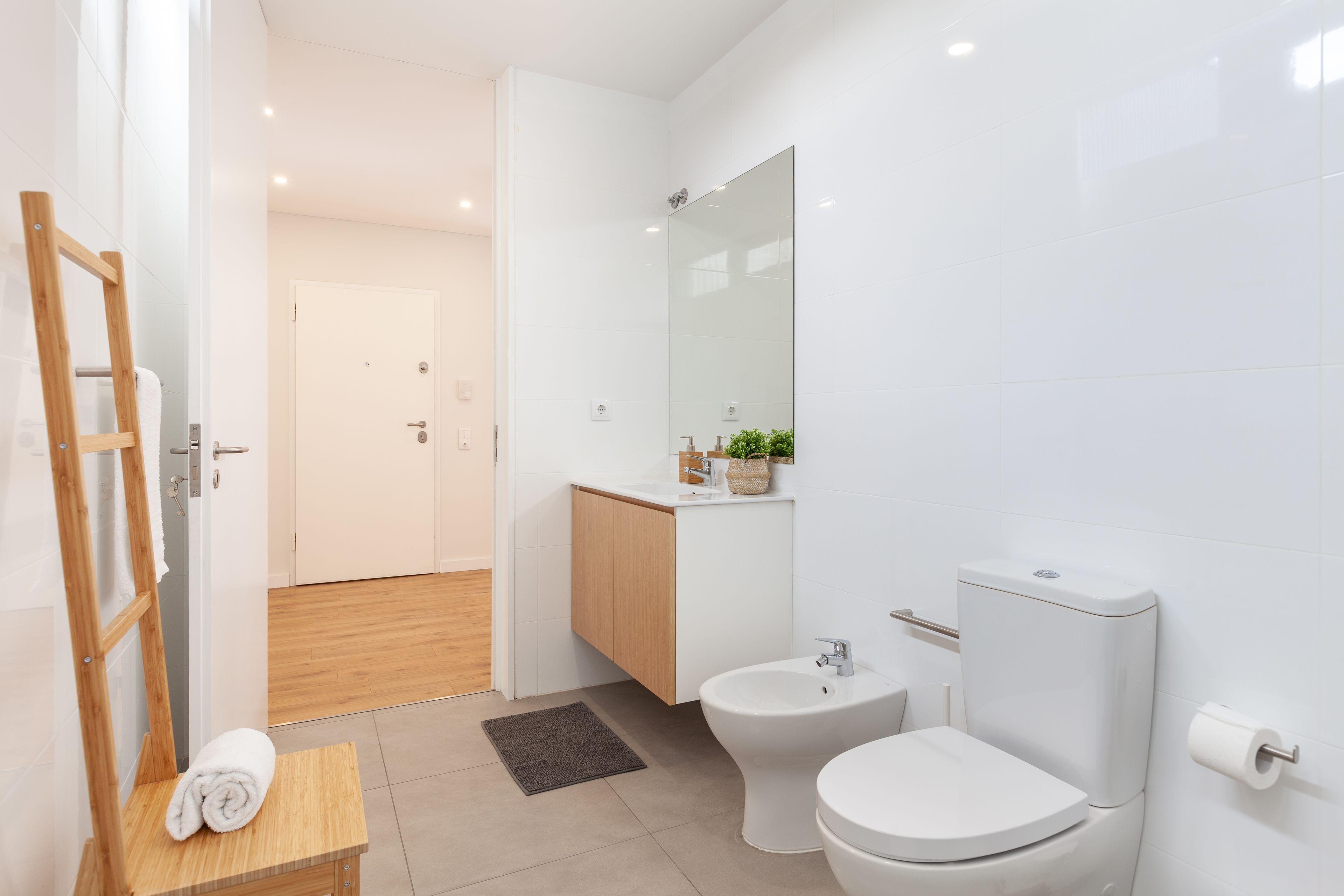 Une salle de bain moderne équipée de toilettes, d’un bidet et d’un meuble-lavabo en bois.