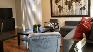 A living room with a television, a world map artwork, a sofa, a coffee table, and a chair.