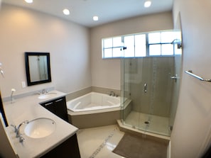 Un baño moderno con una bañera grande, zona de ducha separada y tocador con lavabo.