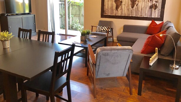 A dining area with a table, chairs, and a television on a cabinet.