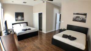 A hotel room with two beds, a ceiling fan, a wardrobe, and a small table with a telephone.