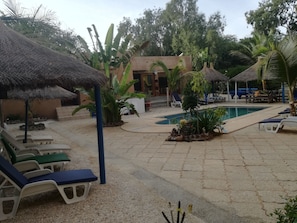 Una piscina al aire libre, sombrillas, sillones reclinables de piscina