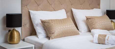 A bed with a tufted headboard, white bedding, and patterned pillows.