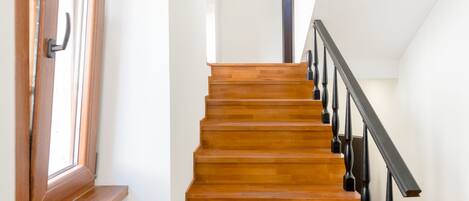 Una escalera de madera con barandales negros que sube a un piso superior.