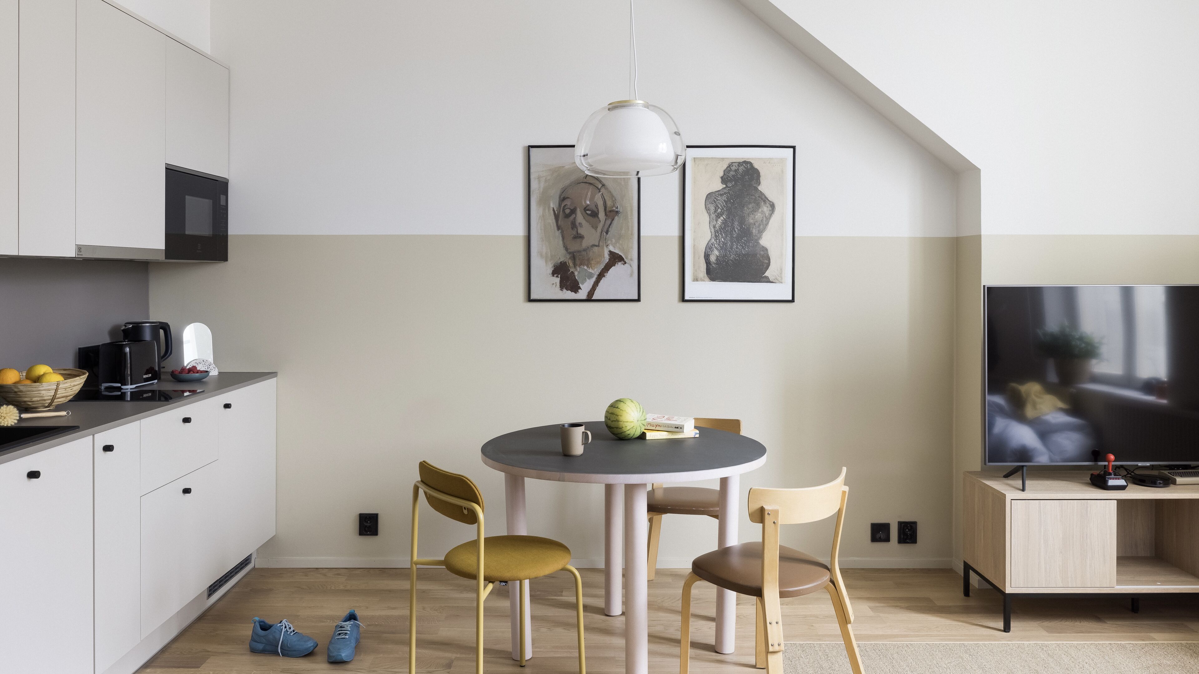 Une cuisine moderne avec un coin repas, un téléviseur et des œuvres d’art accrochées au mur.