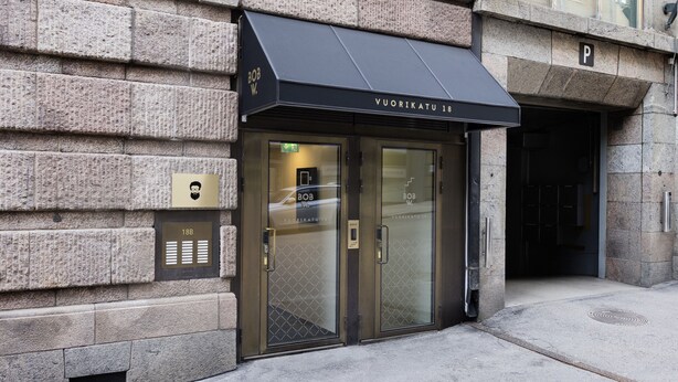A building entrance with a black awning, glass doors, and a stone facade. - Bob W Helsinki City Centre (Helsinki)